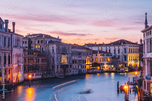 Filtred reflection of boat transport in Venecian gran Canal during evening time for romantic sightseeing on embankment around city, scenery view on ancient architecture buildings in Italy photo