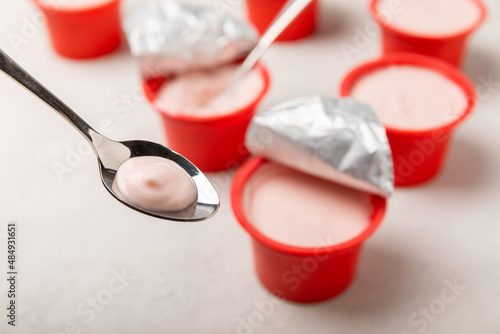 Fototapeta Naklejka Na Ścianę i Meble -  strawberry yogurt in a red plastic cup with a spoon on a white background.