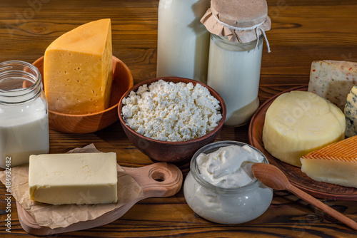 Bottles with milk, cheese, sour cream, butter on a wooden background. Farm organic fresh food. Dairy products photo