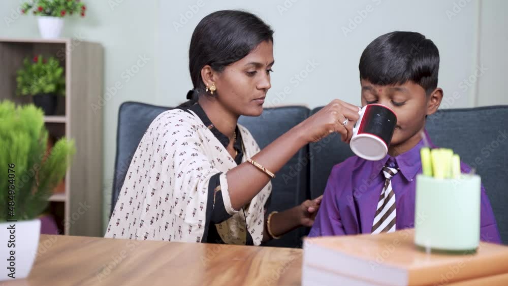 young indian mother forcing kid to drink milk at home before going to school - concept of avoiding refusing food, bothering son and childhood lifestyle young indian mother forcing kid to drink milk at home before going to school - concept of avoiding refusing food, bothering son and childhood lifestyle