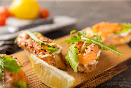 Selection of tasty bruschetta or canapes with salmon.Sandwich with salted salmon, arugula and cream cheese on a wooden board.