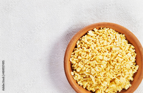  Small flat squares  egg pasta called grattini in plate on white background,yellow  pasta with rough surface  photo