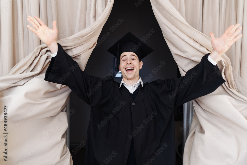 Education, graduation and people concept - happy male student coming out of beige curtains happily on stage