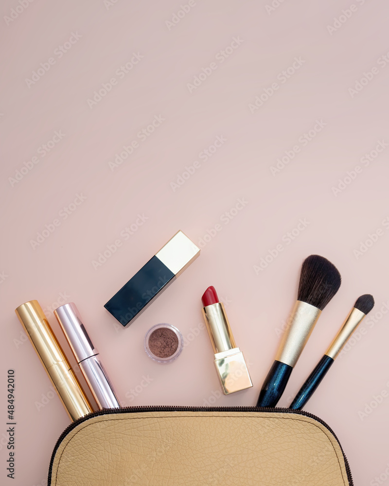 Top view of cosmetics standing out from beige makeup bag on pink background Top view of cosmetics standing out from beige makeup bag on pink background