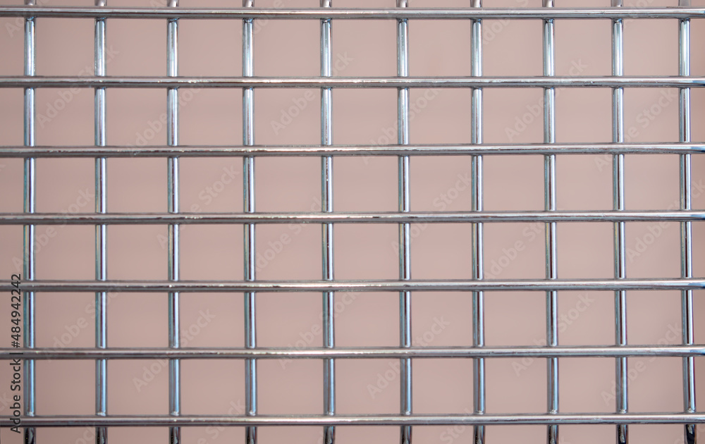 Metal chrome grate with a square mesh on a pink background Metal chrome grate with a square mesh on a pink background