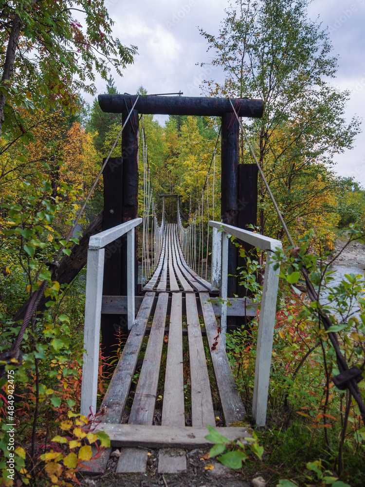 Rope bridge with wooden steps, suspended over the river. Rope bridge with wooden steps, suspended over the river.