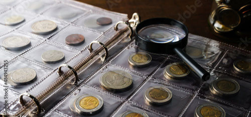 Old collectible coins on a wooden table. Dark background. Banner. Numismatics, Coins in the album. Selective focus.                                                                 photo