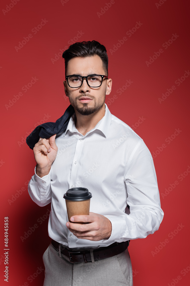 bearded businessman in white shirt and glasses holding blazer and paper cup on red. bearded businessman in white shirt and glasses holding blazer and paper cup on red.