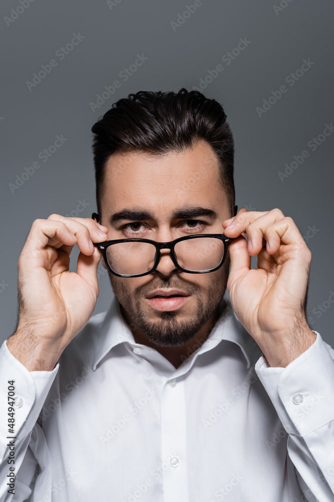 bearded businessman in white shirt adjusting glasses isolated on grey. bearded businessman in white shirt adjusting glasses isolated on grey.