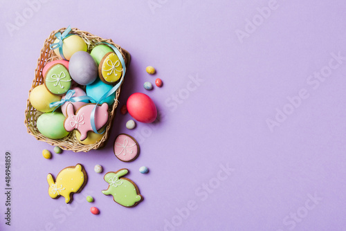 Colorful easter cookies in basket with Multi colors Easter eggs on colored background . Pastel color Easter eggs. holiday concept with copy space