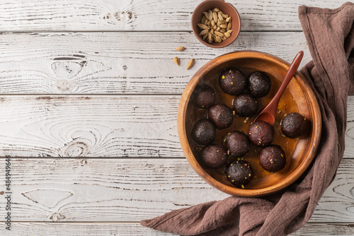 Sweet Gulab Jamun in wooden bowl on rustic background
