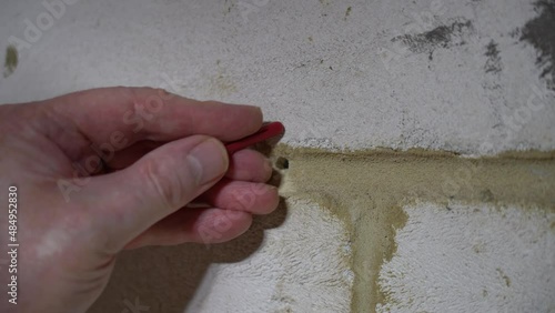 drilling a hole with a  battery operated cordless drill in a clockwork wall and inserting a plastic masonry wall plug 