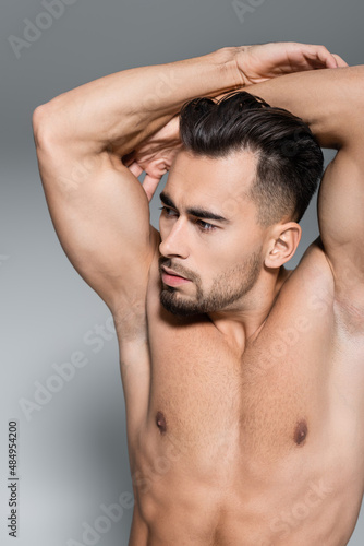 shirtless and muscular sportsman looking away isolated on grey.