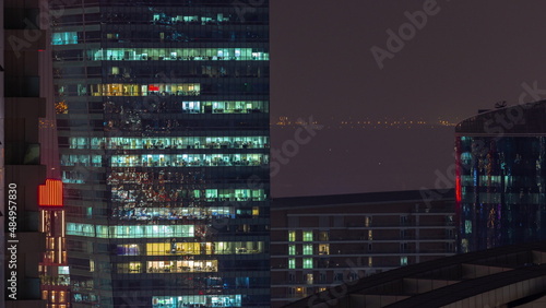 Business Bay Dubai skyscrapers with glowing windows aerial night timelapse.