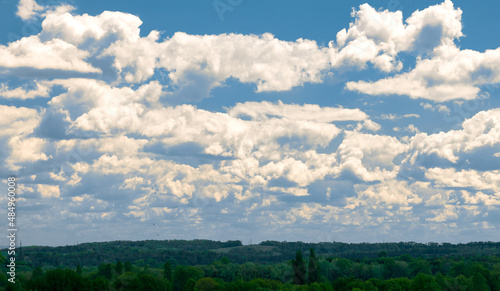 Blue sky with fluffy white clouds. Wide green field under cloudy sky
