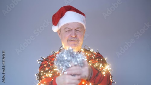 man in red christmas hat wrapped in garland blow up petard celebrating New year