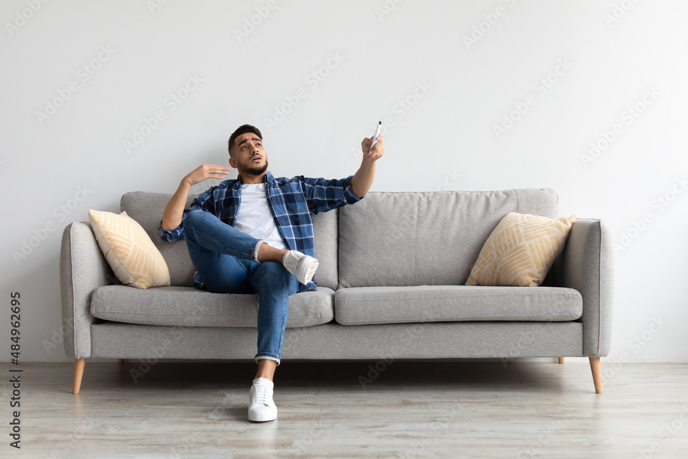 Young man switching on air conditioning at home Young man switching on air conditioning at home