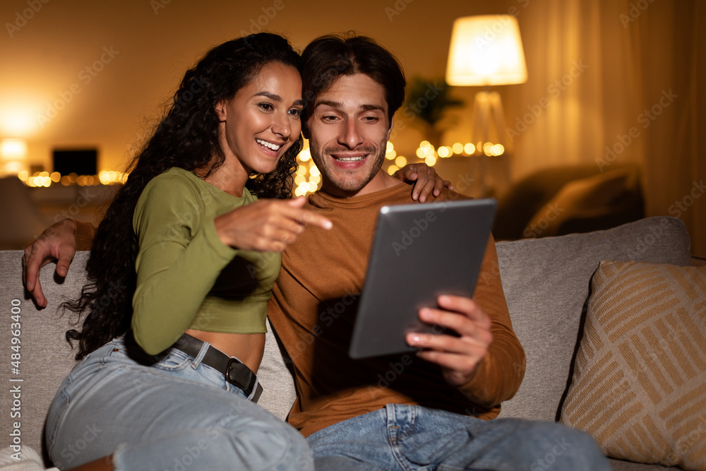 Couple Holding Tablet, Woman Poitning Finger At Computer At Home Couple Holding Tablet, Woman Poitning Finger At Computer At Home