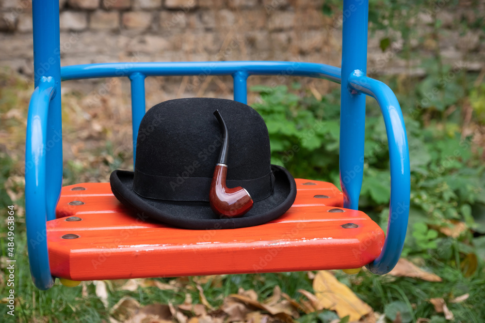 Hat and smoking pipe on a swing close-up