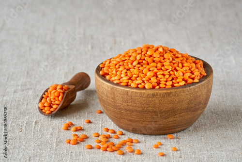 Red lentil  in wooden bowl on linen cloth. Close up photo