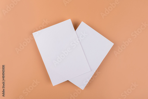 Card mockup of two empty white 5x7 card invitations on beige or terracotta nude background. Minimal simple functional background design with neutral colors