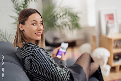 Young woman using phone, navigate social media, while sitting on the sofa at home. Communication