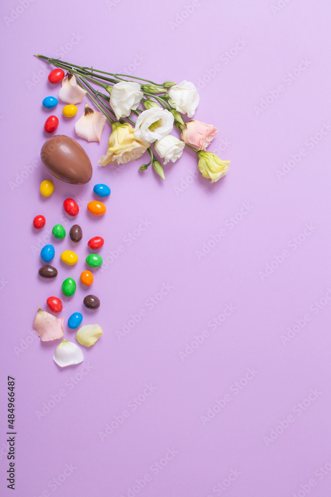easter chocolate eggs and flowers on purple  paper background