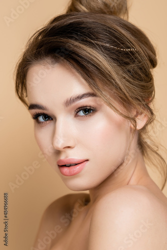 close up portrait of young woman with natural makeup looking at camera isolated on beige.