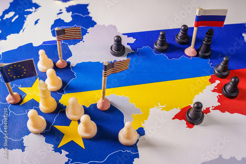 EU, USA and Russian flags with chess pieces symbolizing the conflict and control of Ukraine photo