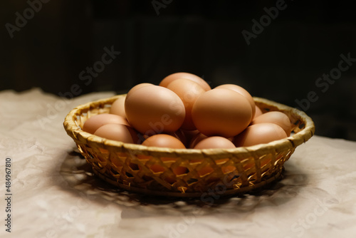 Rustic bowl collection of eggs. Easter craft box with brown eggs on eco background. Chicken eggs on craft table with hay and straw. Close-up view of raw product. Wooden straw. Bio and organic
