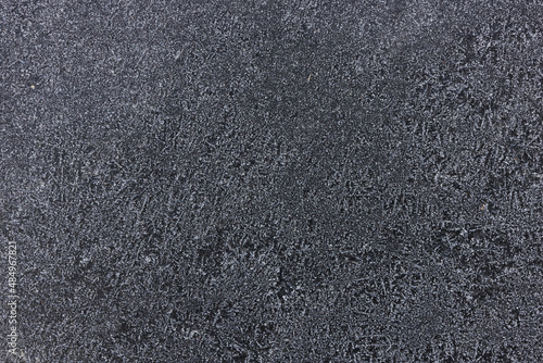 Frozen pattern of hoarfrost and frostwork structure on the dark windshield glass. Color photo for background. 