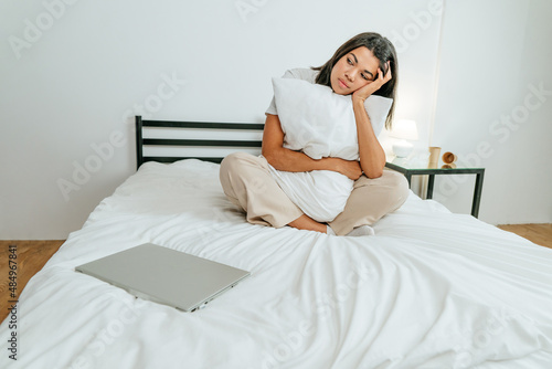 Young woman sitting on the bed with closed laptop © lithiumphoto