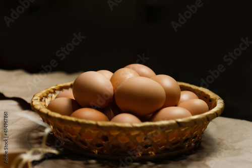 Rustic bowl collection of eggs on black background. Easter craft box with brown eggs on eco background. Chicken eggs on craft table with hay and straw. Close-up view of raw product. Wooden straw