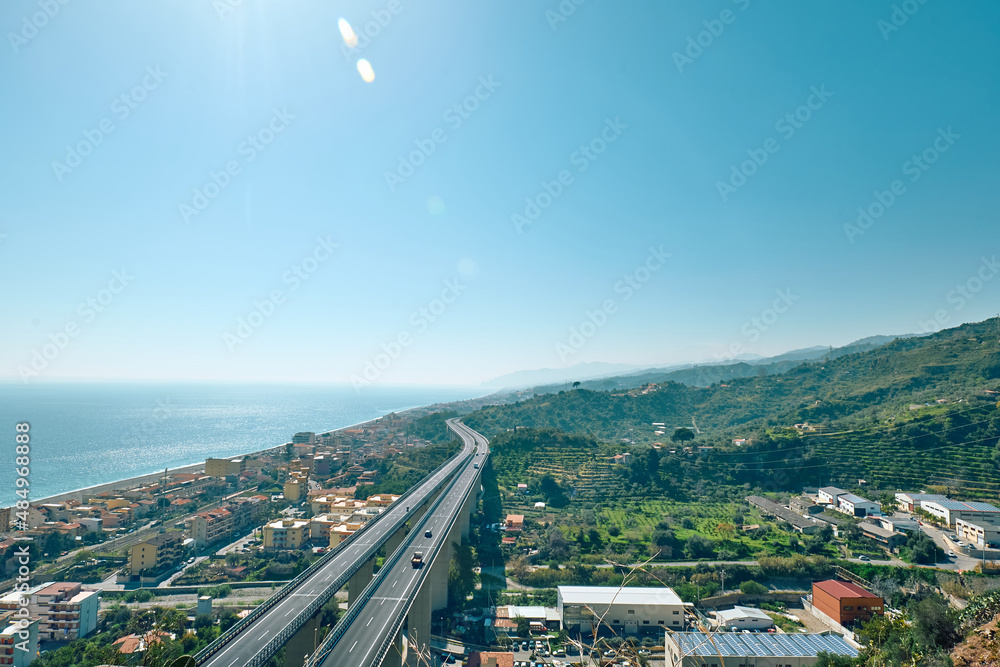 View on the Ionian coast with the typical coastal villages and the meandering highway. Mediterranean Sea. Sicily.