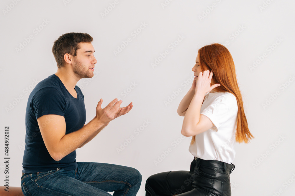 © dikushin - Studio shot of resentful dissatisfied young couple quarreling, actively gesturing with hands, talking and shouting at each other on white isolated background. Concept of relationship crisis. © dikushin - Studio shot of resentful dissatisfied young couple quarreling, actively gesturing with hands, talking and shouting at each other on white isolated background. Concept of relationship crisis.