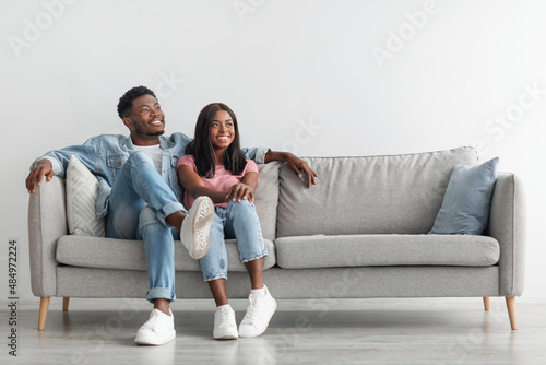 African American couple spending weekend together sitting on couch