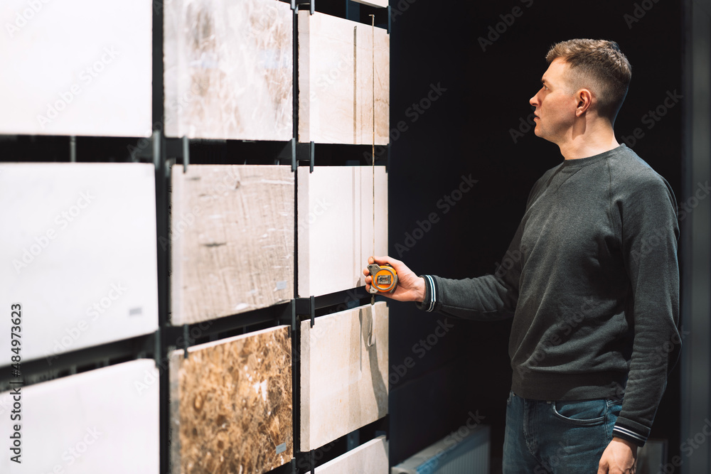 a man stands near a stand with granite and a tape measure measures the dimensions a man stands near a stand with granite and a tape measure measures the dimensions