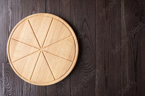 Round pizza cutting board with slice grooves on wooden table top view