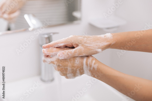Washing hands under the flowing water tap. Hygiene concept hand detail. Washing hands rubbing with soap for corona virus prevention, hygiene to stop spreading corona virus in or public wash room.