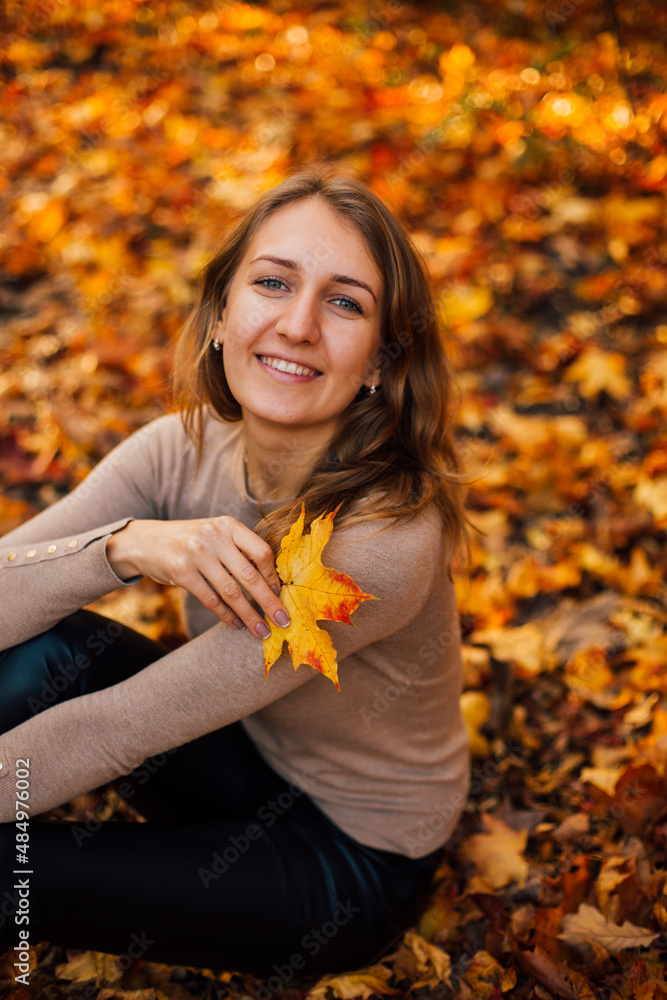 Beautiful girl is sitting on yellow leaves in the park. Attractive woman wearing beige sweater and black pants is walking in autumn park. Bright, warm sunny autumn day with yellow background.
Beautiful girl is sitting on yellow leaves in the park. Attractive woman wearing beige sweater and black pants is walking in autumn park. Bright, warm sunny autumn day with yellow background.