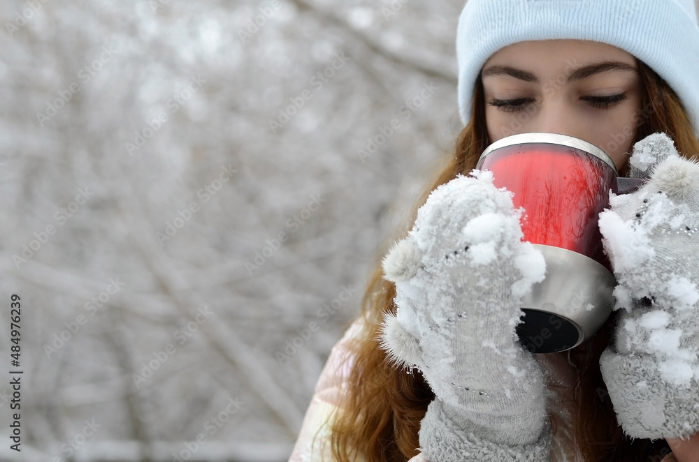 A red cup with hot tea in the hands of the girl. Selective sharpness. A red cup with hot tea in the hands of the girl. Selective sharpness.