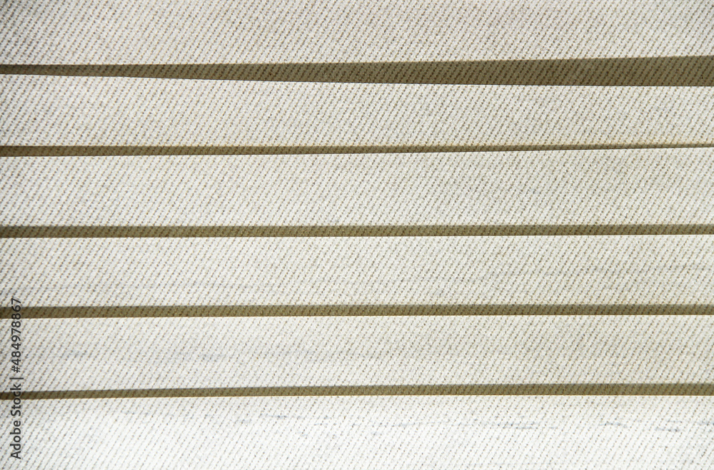 Fototapeta premium Vertical blind in horizontal background. Horizontal line pattern. White cloth curtain. Straight-line wallpaper. Shade and shadow on the white wall.