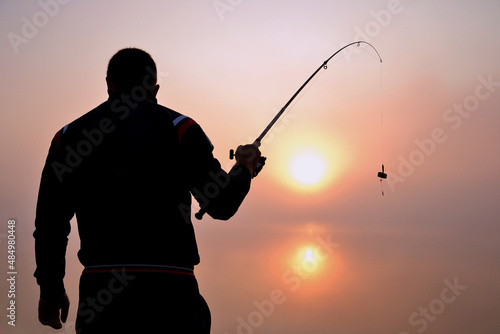 Young man fishing on the shore at dawn