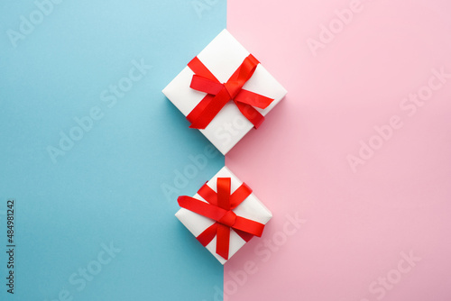 White boxes with gifts on a blue and pink background. St. Valentine's Day. Concept of love and spring. Top view, background, copy space 