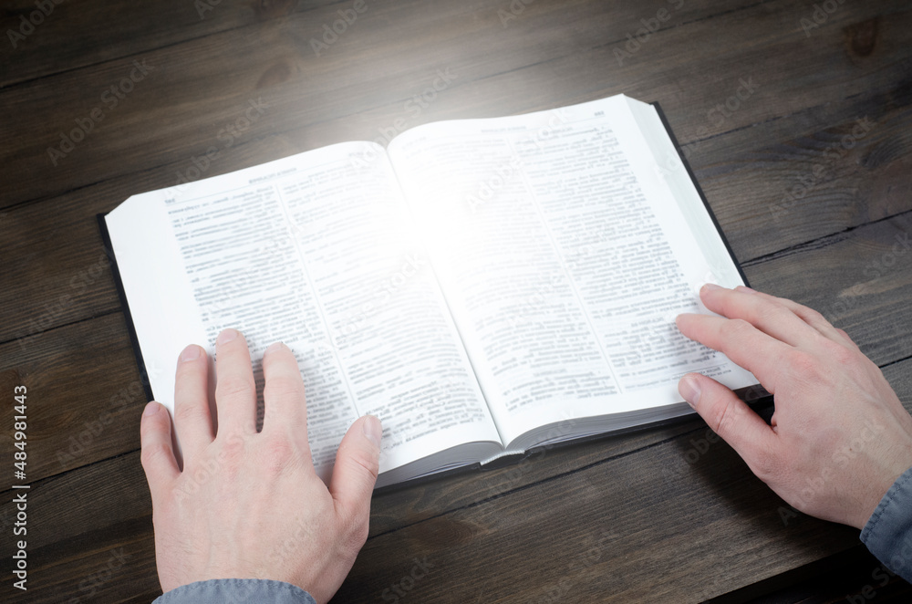 Fototapeta premium Prayer. Open Bible. Hands folded in prayer. The man is praying. Hands on the table. 