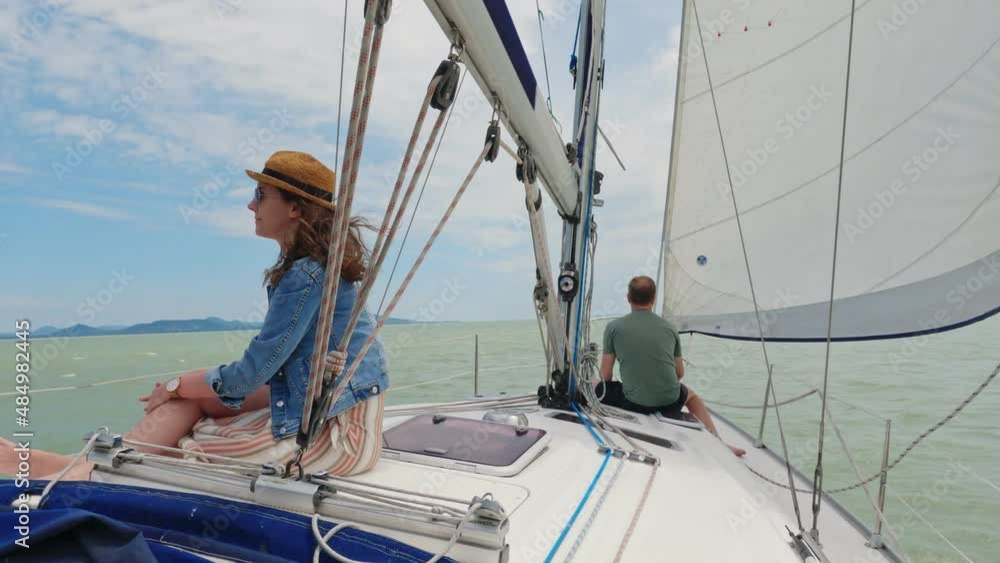Young woman relaxing on sailing boat enjoying summer vacation. Wind, hat, sunglasses, traveling, copy sapce .