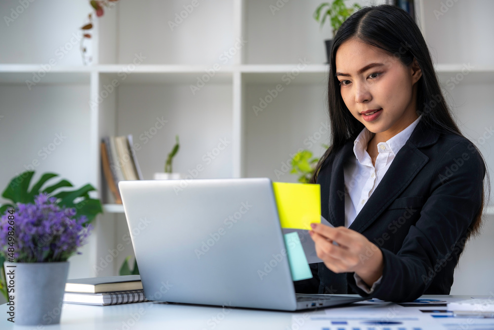 Asian businesswoman working on tablet and taking notes, accountant use a computer laptop at work in the office. Asian businesswoman working on tablet and taking notes, accountant use a computer laptop at work in the office.