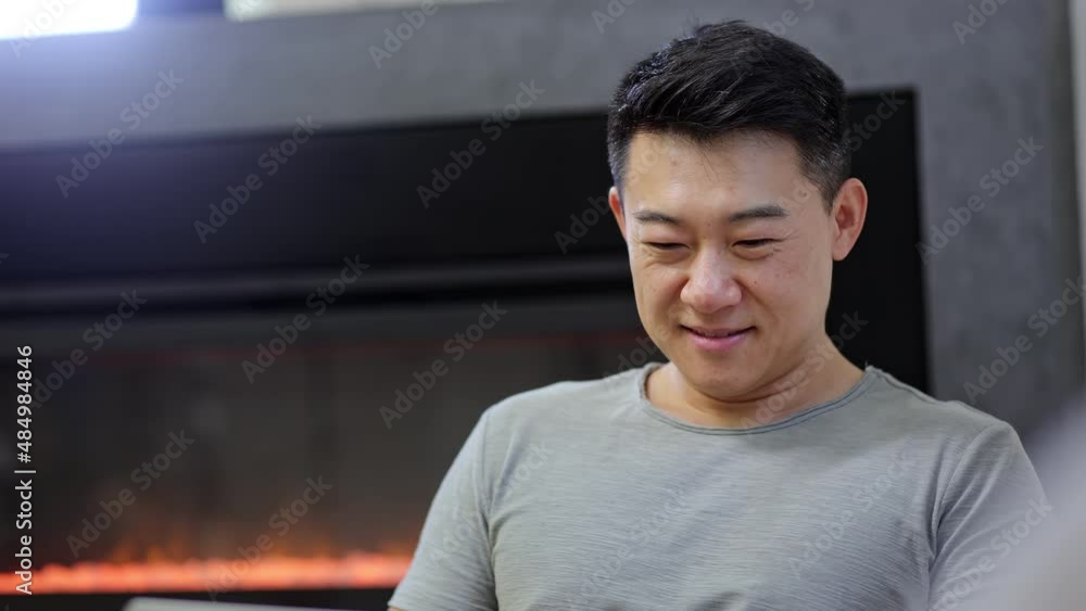 Asian man smiling working with laptop, modern design. Man relaxing on the sofa. Use a modern laptop. Asian man smiling working with laptop, modern design. Man relaxing on the sofa. Use a modern laptop.