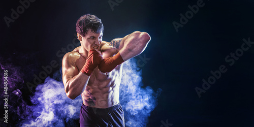 Kickboxer delivering an elbow hit isolated on smoke background. Sport concept, mixed martial arts