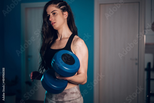 Athlete female lifting dumbbells during her fitness training at home